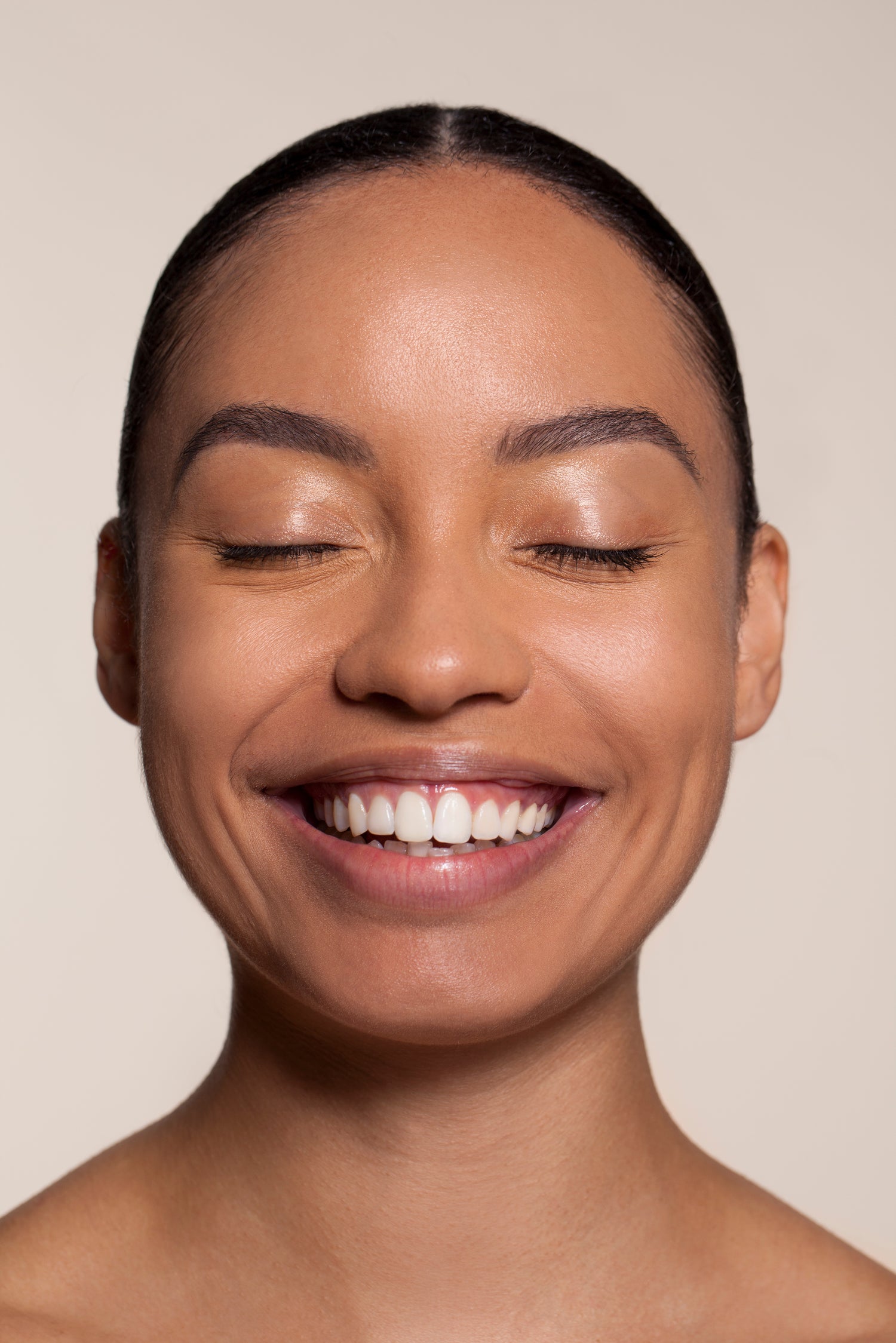 Woman with a radiant smile against a beige background