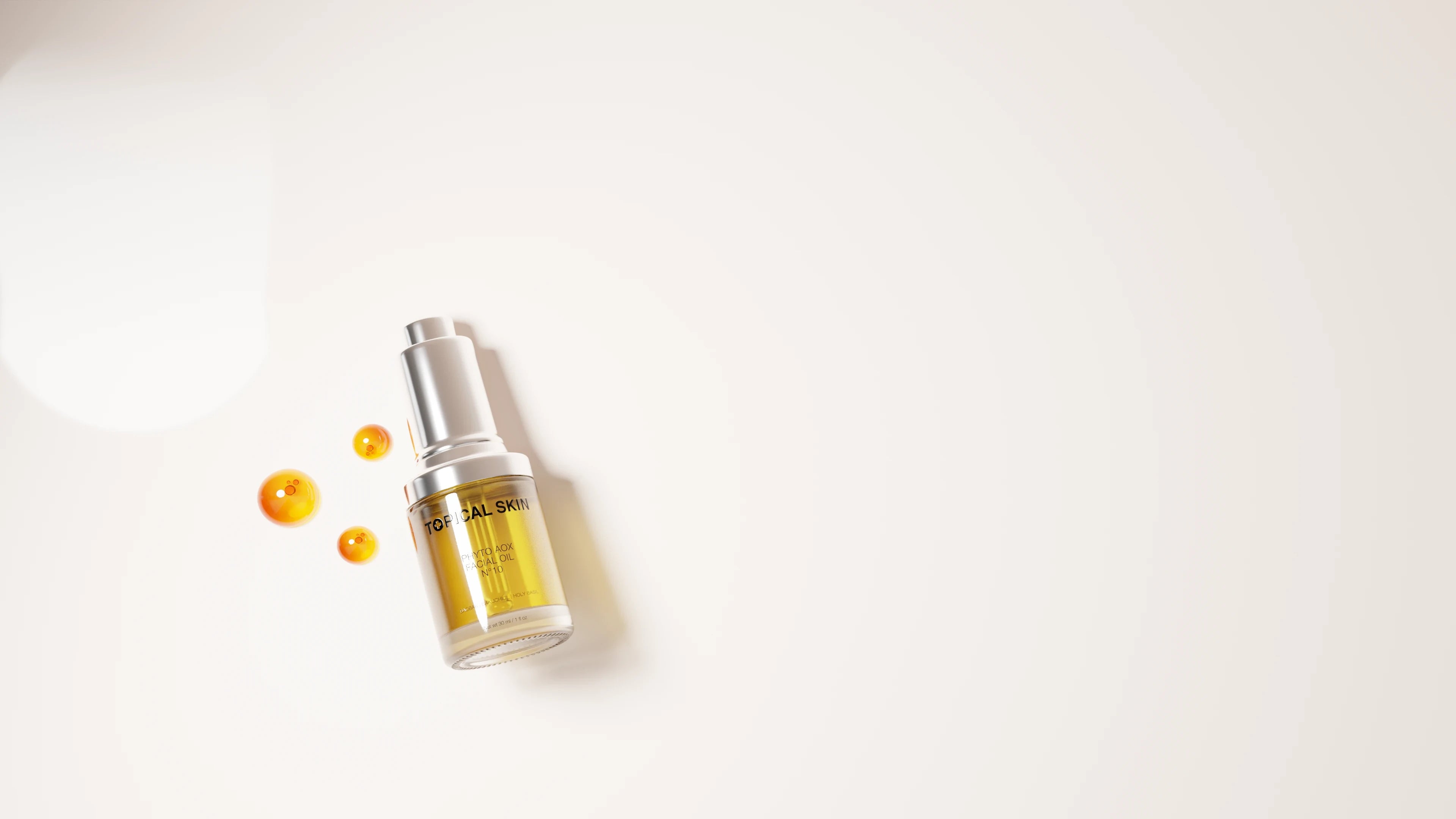Topical skincare serum bottle with amber oil and silver pump, beside glowing orange droplets on a white background.