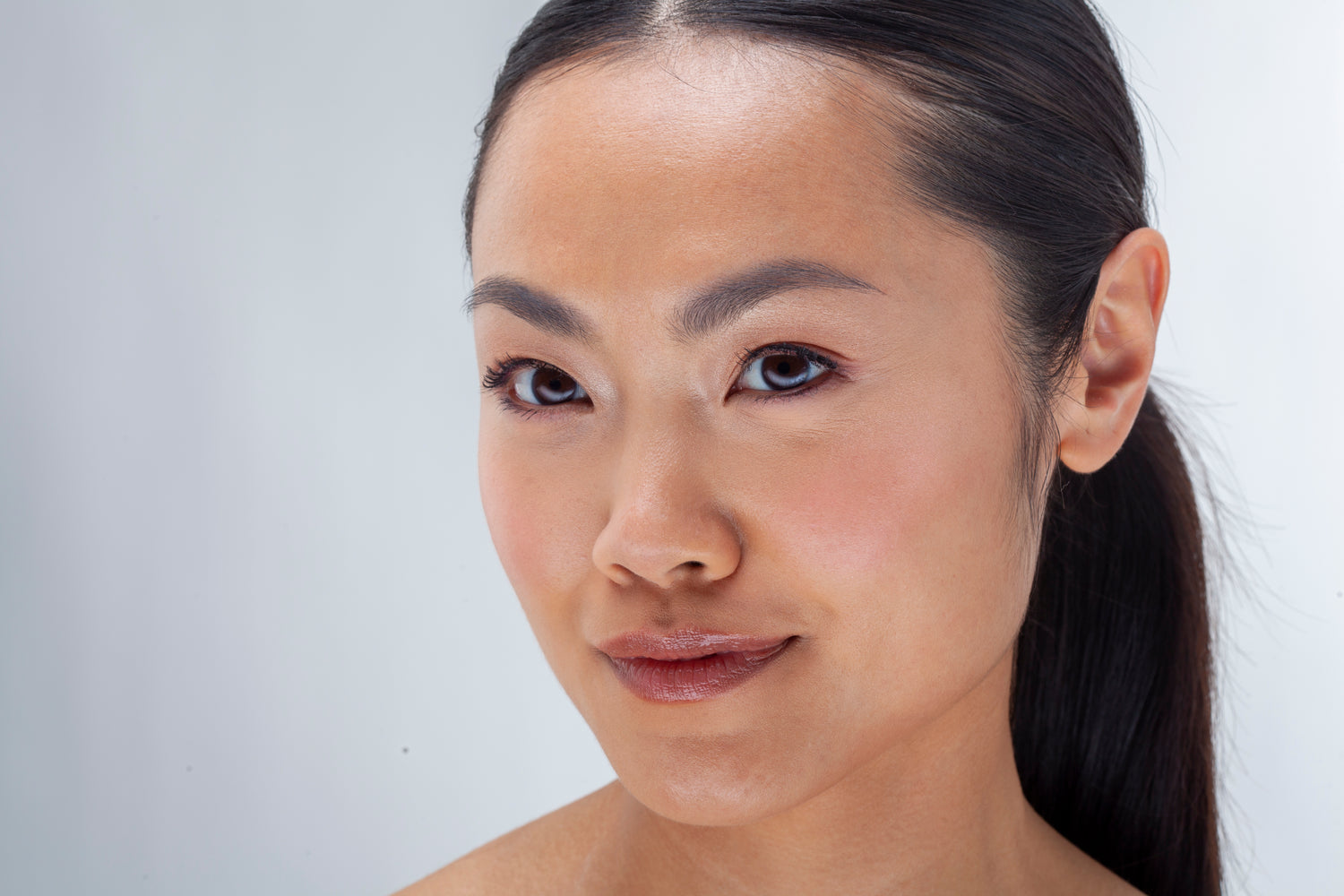 Close-up of a woman with a neutral expression on a plain background
