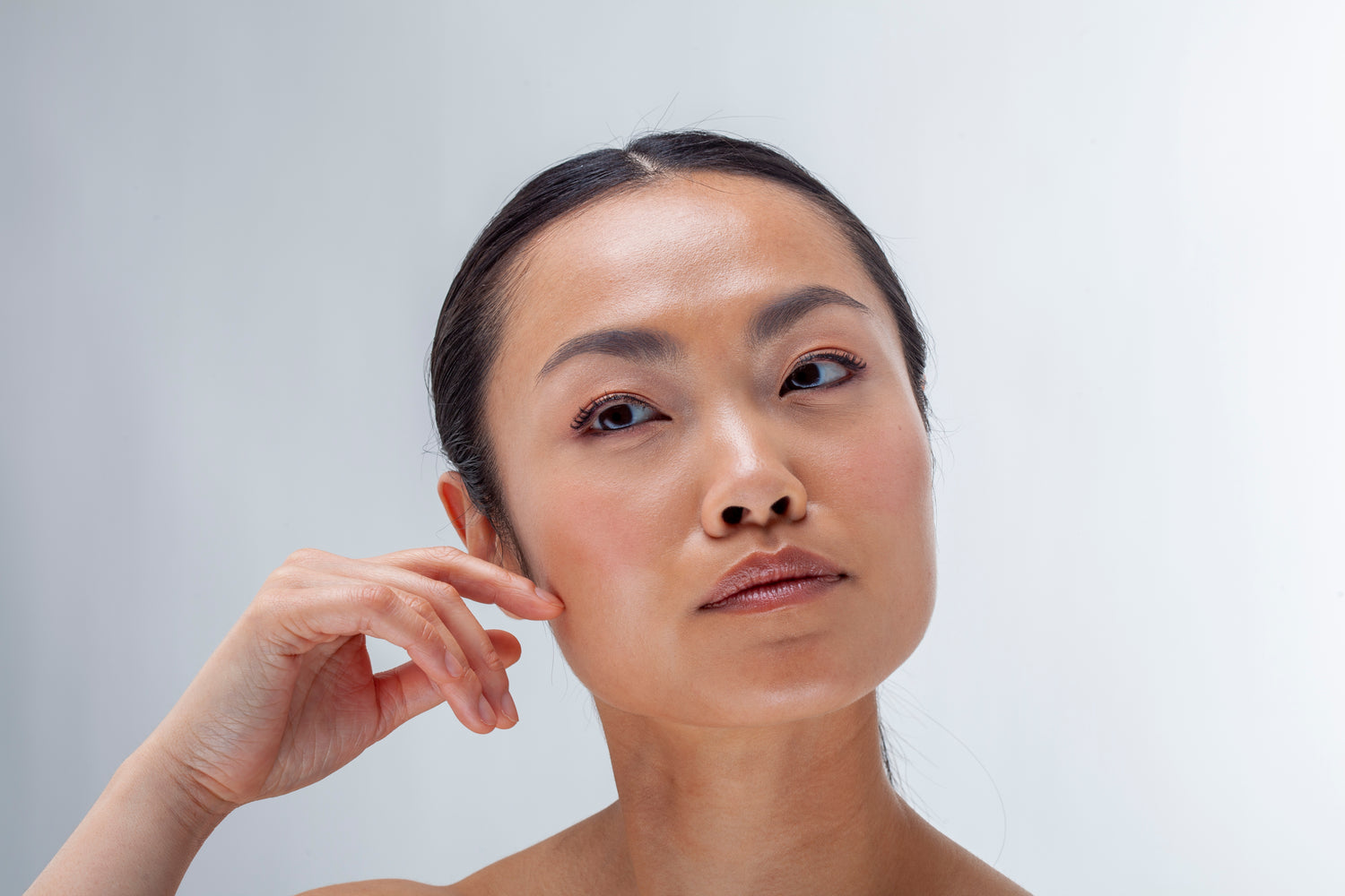 Woman touching her ear against a plain background